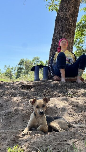 Momento de descanso apoiado em uma árvore, com um cachorro por perto